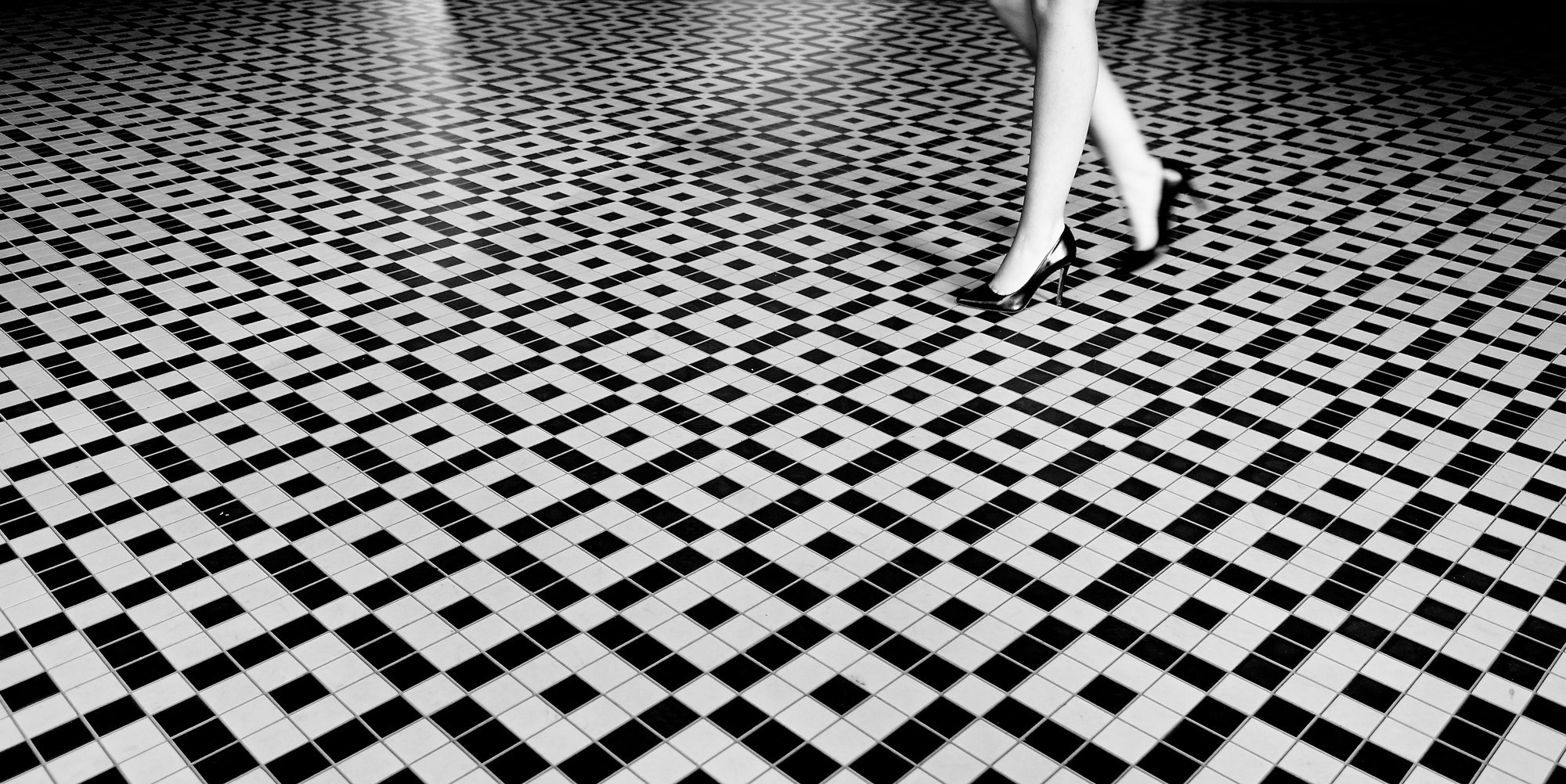Woman's legs with high heels wlking on tiled floor