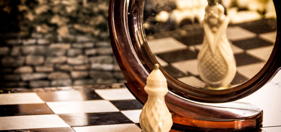 A chess game token looking at the mirror and seeing themselves bigger